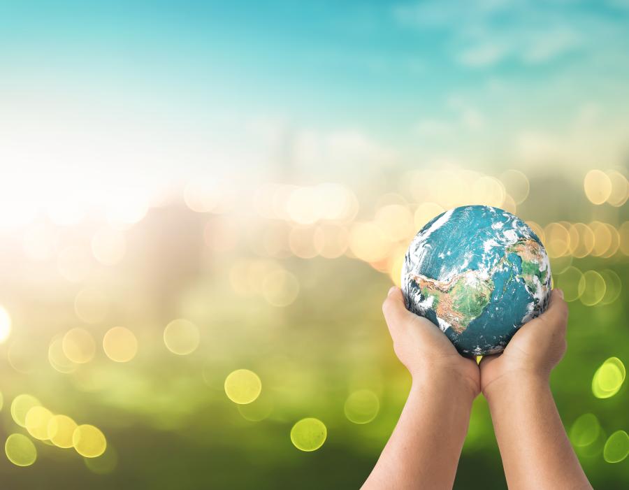 hands holding a globe in front of abstract environmental background
