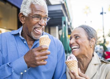 Older Black man and woman eating ice cream and smiling