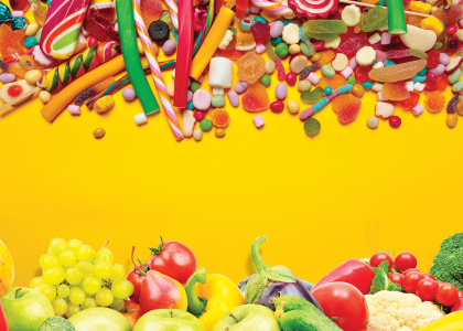 A yellow background with candy at the top and fruits and vegetables at the bottom.