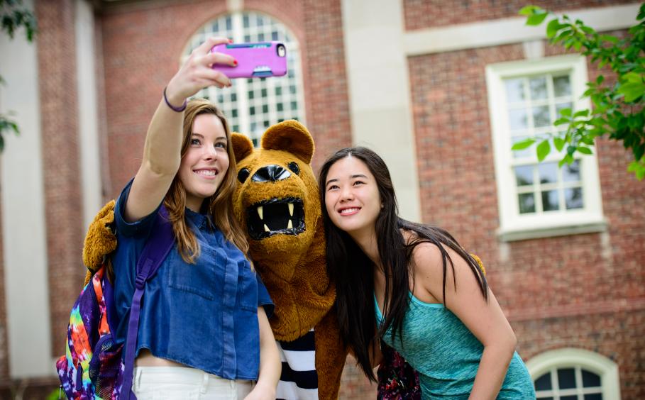 Students on campus with the Nittany Lion mascot. 