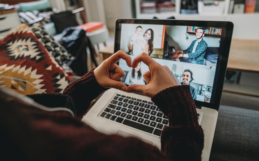 Person holding their hands in the shape of a heart during a video conference with family and friends.