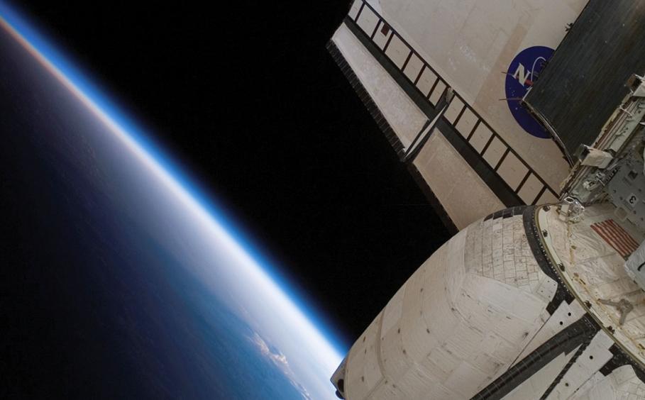 Close up of the backend of a space shuttle with a section of the earth in the background. 