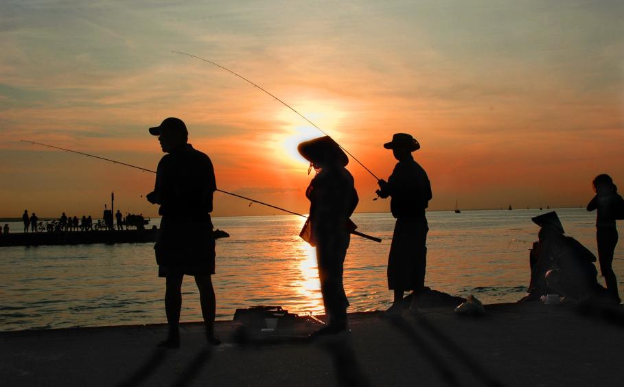 Fishermen silhouetted on setting sun