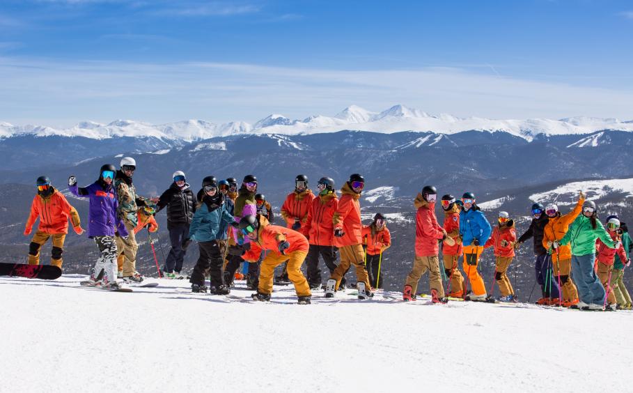 Skiers and Snowboarders on top of a mountain smiling