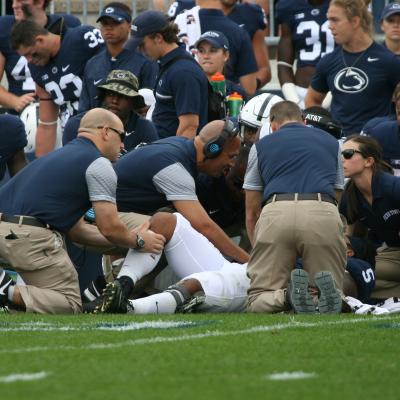 Athletic trainers working a player on the sidelines.