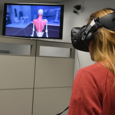 A student in a VR headset and a display of the human body
